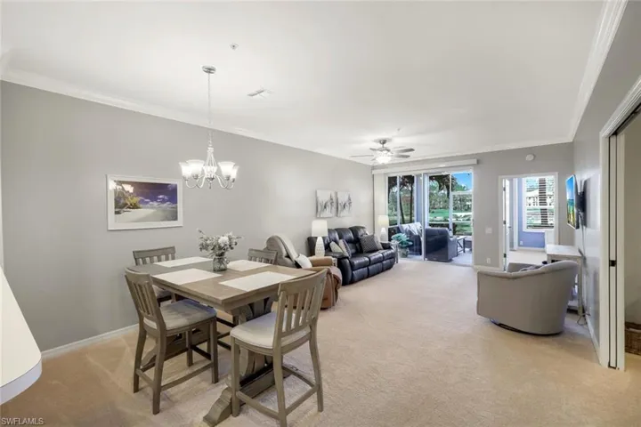 Dining area featuring light carpet, crown molding, and ceiling fan with notable chandelier