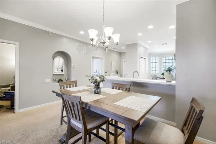 Dining area featuring crown molding, light carpet, and an inviting chandelier