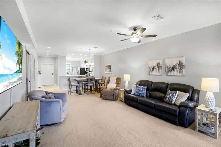 Carpeted living room with crown molding and ceiling fan