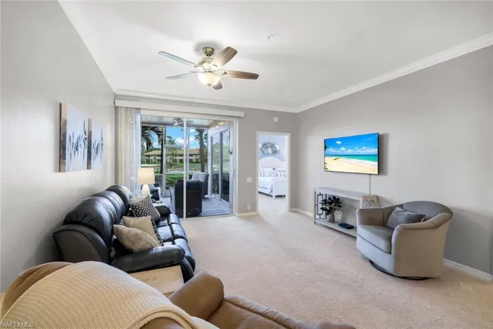 Living room featuring light colored carpet, ceiling fan, and crown molding