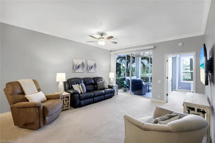 Living room featuring ceiling fan, ornamental molding, and light carpet
