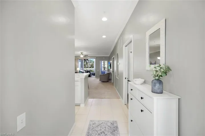 Hallway featuring light colored carpet and crown molding