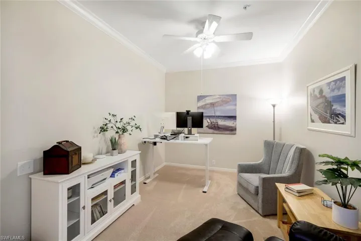Living area with light carpet, ceiling fan, and ornamental molding