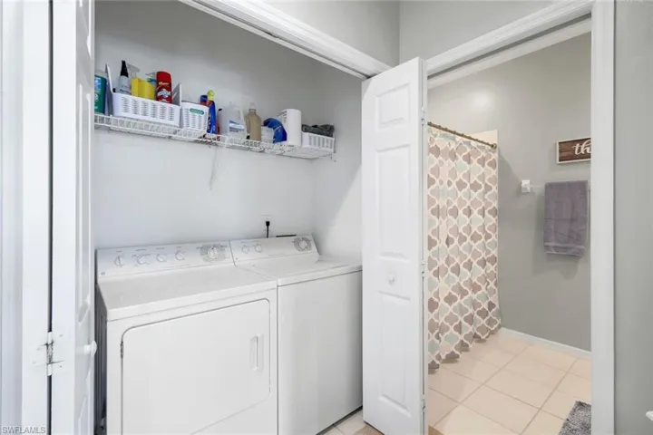 Clothes washing area with independent washer and dryer and light tile patterned floors