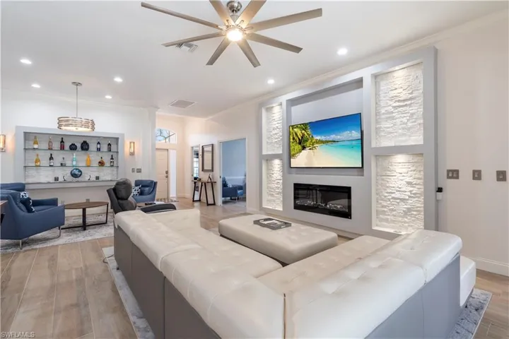 Living room with ceiling fan, light hardwood / wood-style floors, and ornamental molding
