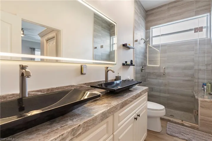 Bathroom with hardwood / wood-style floors, vanity, an enclosed shower, and toilet