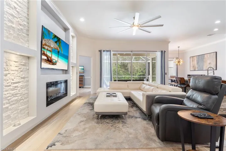 Living room with crown molding, light hardwood / wood-style flooring, and ceiling fan with notable chandelier