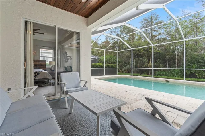 View of swimming pool featuring glass enclosure and a patio