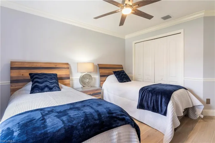 Bedroom with hardwood / wood-style flooring, ceiling fan, ornamental molding, and a closet