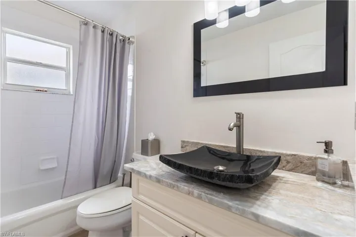 Full bathroom featuring shower / tub combo with curtain, vanity, and toilet