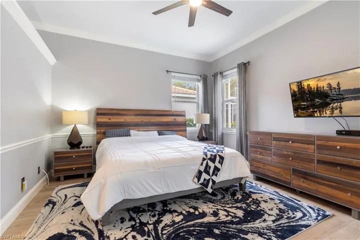 Bedroom featuring ceiling fan, light hardwood / wood-style floors, and crown molding