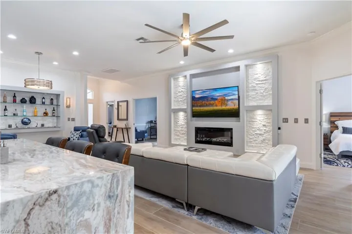 Living room with ceiling fan, light hardwood / wood-style floors, and ornamental molding