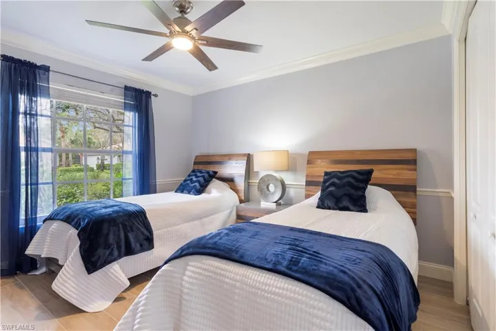 Bedroom featuring ceiling fan, wood-type flooring, crown molding, and a closet
