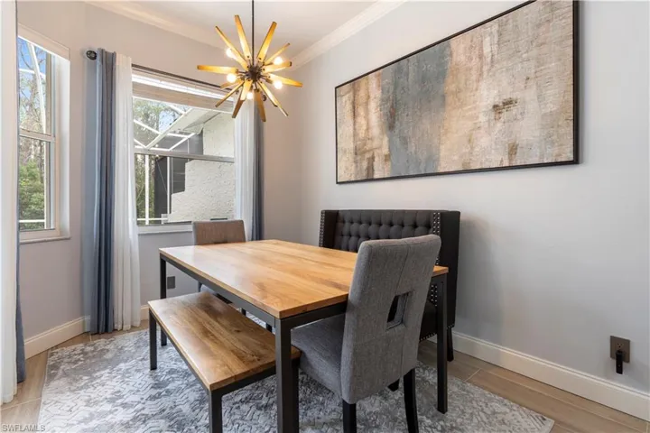 Dining room featuring a wealth of natural light, crown molding, light wood-type flooring, and an inviting chandelier