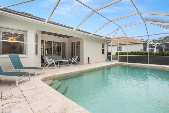 View of pool featuring a patio, glass enclosure, and ceiling fan