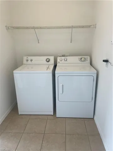 Washroom with light tile patterned flooring and separate washer and dryer