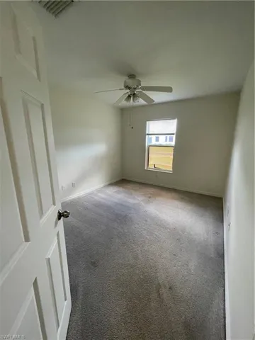Carpeted spare room featuring baseboards