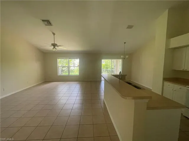 Unfurnished living room featuring light tile patterned flooring, ceiling fan, and a chandelier