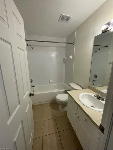 Bathroom with shower / bathtub combination, vanity, and light tile patterned flooring