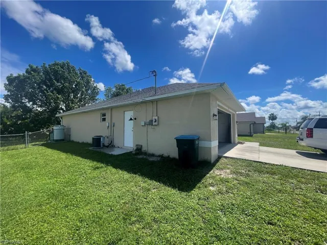 Rear view of property featuring stucco siding, a garage, and driveway