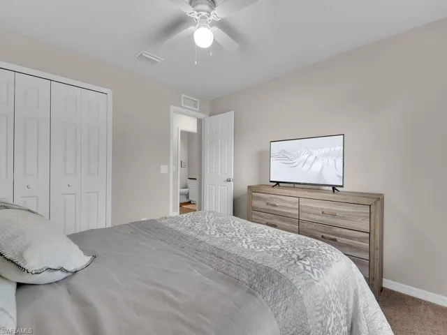 Bedroom with a tray ceiling, carpet flooring, ensuite bathroom, a walk in closet, and ceiling fan