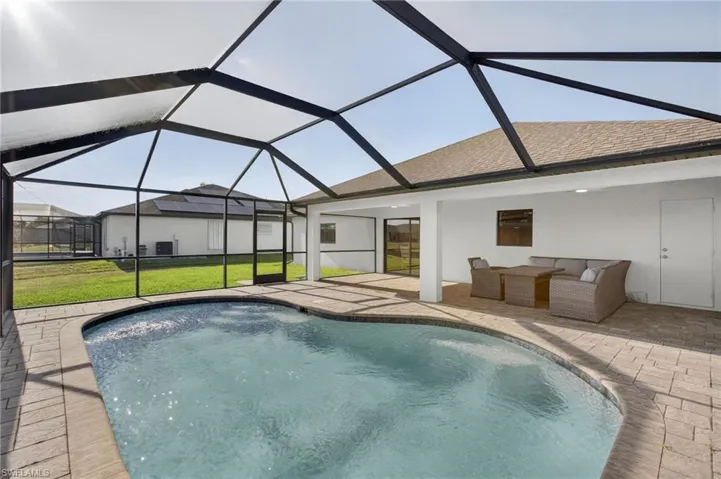 Outdoor pool featuring a patio area, a lawn, and glass enclosure