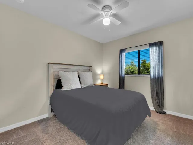 Bedroom featuring a raised ceiling, carpet, and a ceiling fan