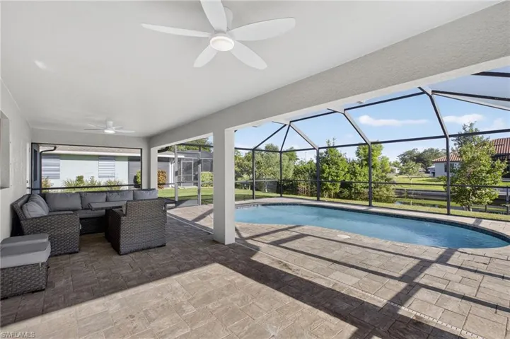 Swimming pool featuring a ceiling fan, a patio area, an outdoor living space, and glass enclosure