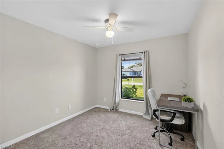 Carpeted home office featuring baseboards and a ceiling fan