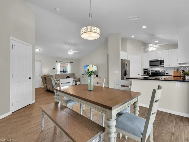 Kitchen featuring dark countertops, appliances with stainless steel finishes, a peninsula, lofted ceiling, and wood finished floors