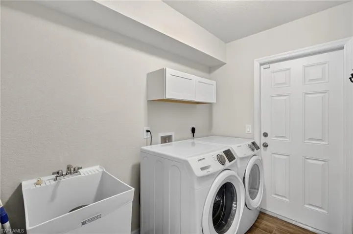 Laundry area with independent washer and dryer, dark wood-style flooring, a textured ceiling, cabinet space, and a textured wall