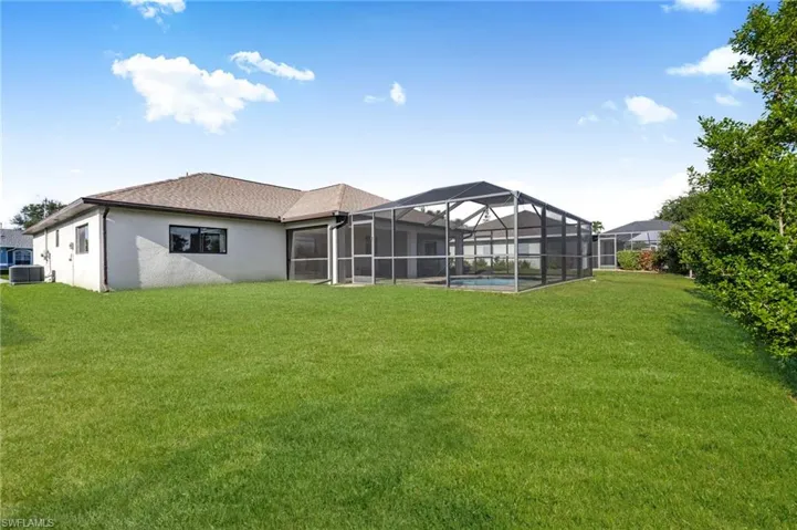 Back of property with a lawn, stucco siding, and glass enclosure