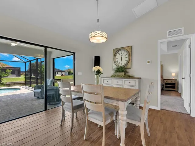 Kitchen featuring decorative backsplash, appliances with stainless steel finishes, lofted ceiling, a peninsula, and light wood-style floors