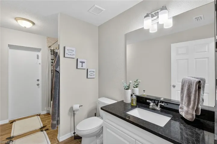 Bathroom featuring wood finished floors, vanity, a shower with curtain, and a textured ceiling