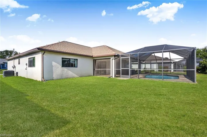 Rear view of property with a lawn, stucco siding, an outdoor pool, a lanai, and a patio