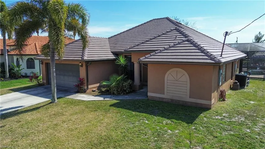 View of front facade with a front lawn, a garage, a tiled roof, and stucco siding
