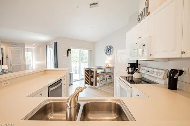 Kitchen featuring a healthy amount of sunlight, sink, light hardwood / wood-style flooring, and white appliances