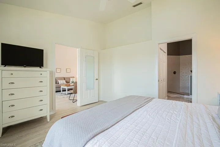 Master Bedroom with ensuite bath, a towering ceiling, light wood-type flooring, and ceiling fan