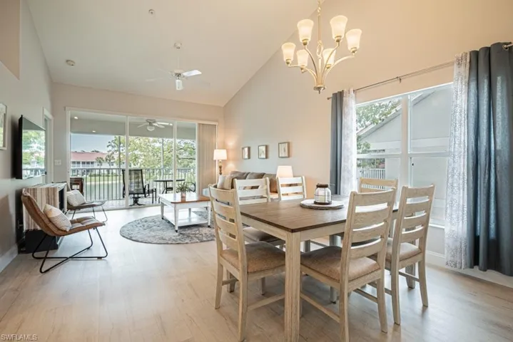 Dining room featuring high vaulted ceiling, ceiling fan with notable chandelier, plenty of natural light, and light wood-type flooring