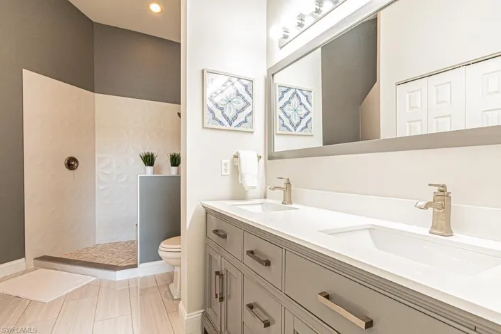 Master Bathroom with toilet, vanity, a tile shower, and tile patterned flooring