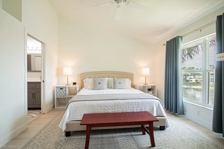 Bedroom featuring lofted ceiling, ensuite bathroom, light wood-type flooring, and ceiling fan