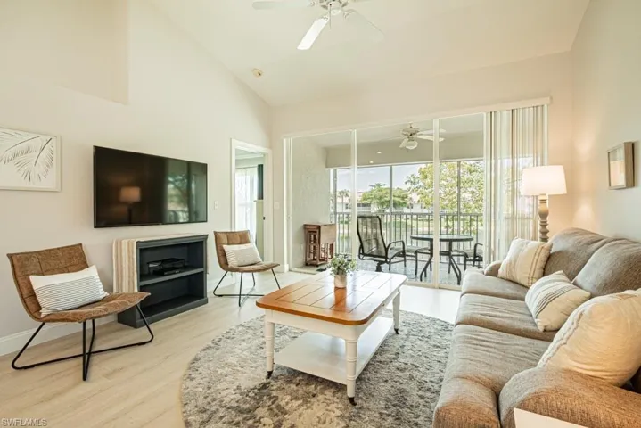 Living room featuring ceiling fan, high vaulted ceiling, and light wood-type flooring