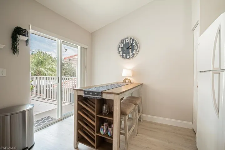 Dining area with vaulted ceiling and light wood-type flooring