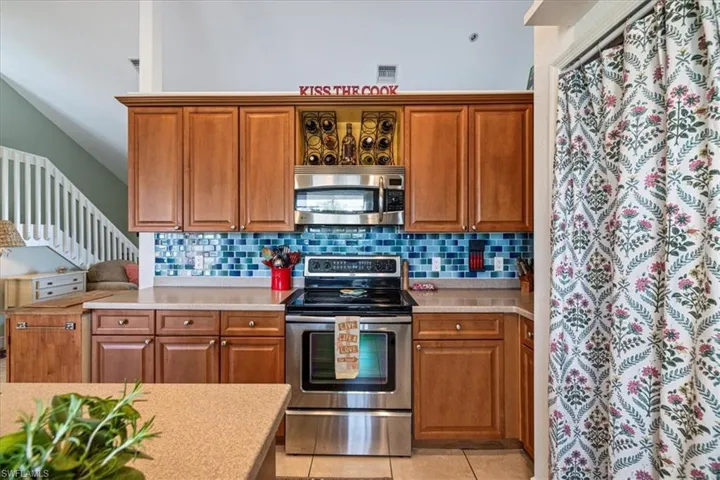 Kitchen with light tile patterned flooring, backsplash, and appliances with stainless steel finishes