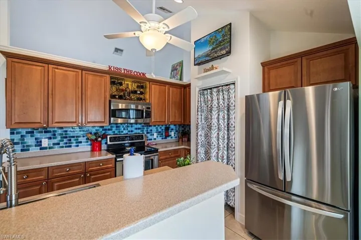 Kitchen featuring tasteful backsplash, stainless steel appliances, ceiling fan, lofted ceiling, and light tile patterned flooring