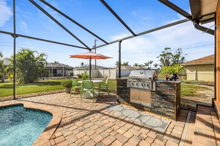 View of patio with an outdoor kitchen, a lanai, and grilling area