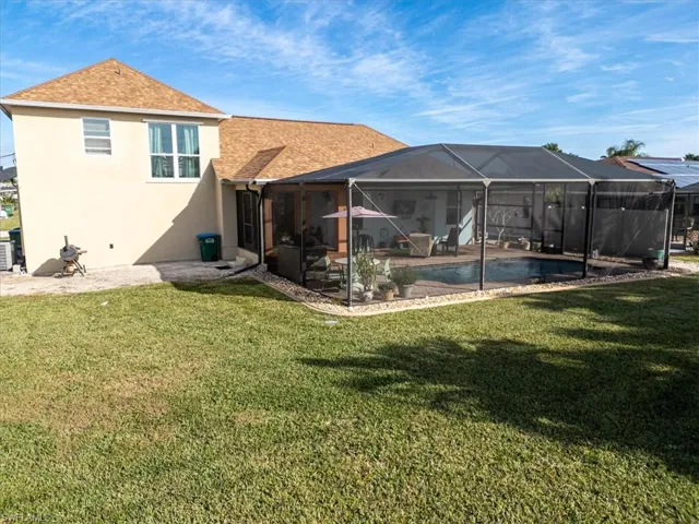 Rear view of property with a lanai and a lawn