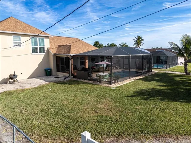 Back of house with a lanai, a yard, and a patio