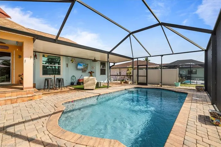 View of swimming pool featuring glass enclosure and a patio