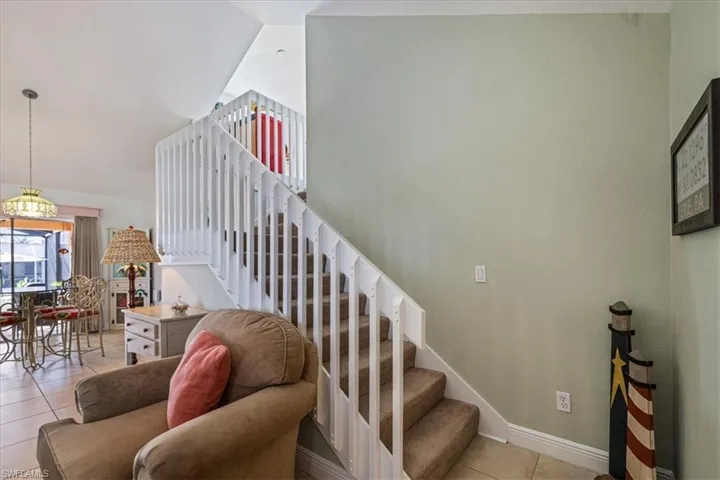Stairs featuring tile patterned flooring and lofted ceiling